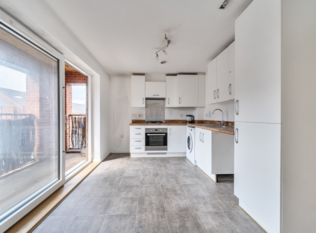 Kitchen with fitted units, integrated oven and sliding balcony doors.