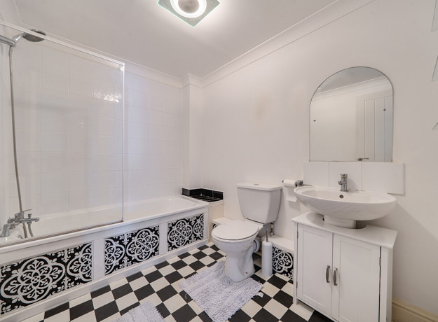 Bathroom with bath, toilet, sink and mirrored cabinet.