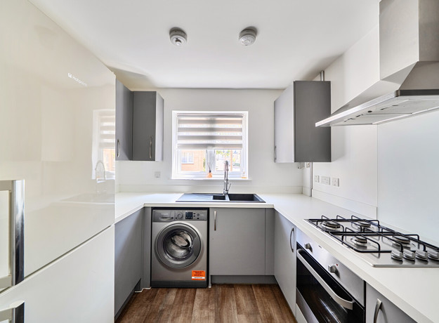 Kitchen with fitted units, gas hob and washing machine.