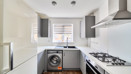 Kitchen with fitted units, gas hob and washing machine.