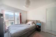 Bedroom with bed near glass floor-to-ceiling window, side table, and wardrobe.