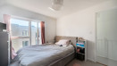 Bedroom with bed near glass floor-to-ceiling window, side table, and wardrobe.