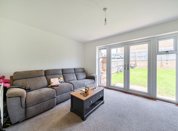Living room with sofa, coffee table, and patio doors to the garden.