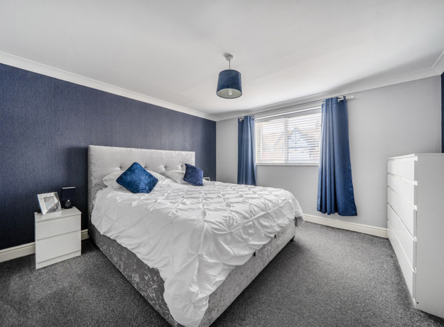 Bedroom with double bed, bedside tables, wardrobe and window.