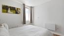 Bedroom with bed, wall art, window, curtains, and wooden flooring.