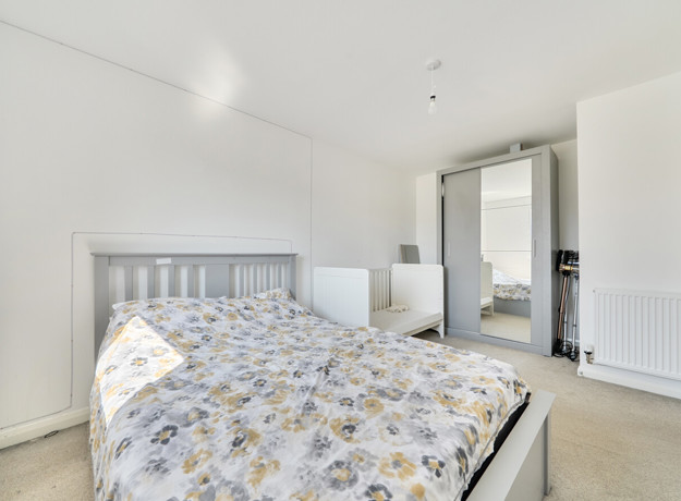 Bedroom with double bed, cot, and wardrobe with mirrored doors.