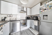 Modern kitchen with white cabinets, appliances and tiled splashback.