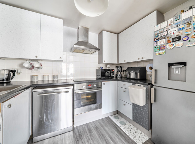 Modern kitchen with white cabinets, appliances and tiled splashback.