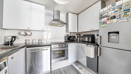 Modern kitchen with white cabinets, appliances and tiled splashback.